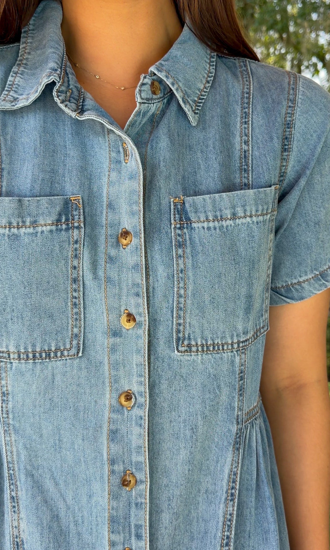 Light wash chambray midi dress featuring a collared neckline, functional button-front closure, oversized chest pockets, short sleeves, side pockets, and a relaxed silhouette.