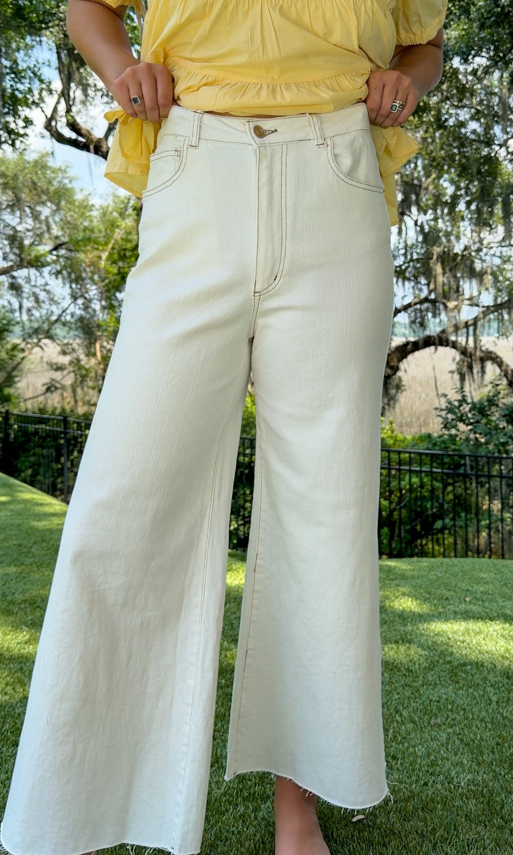 White high-rise wide leg denim jeans featuring contrast stitching, a cropped raw hem, front and back pockets, and a flattering structured fit.