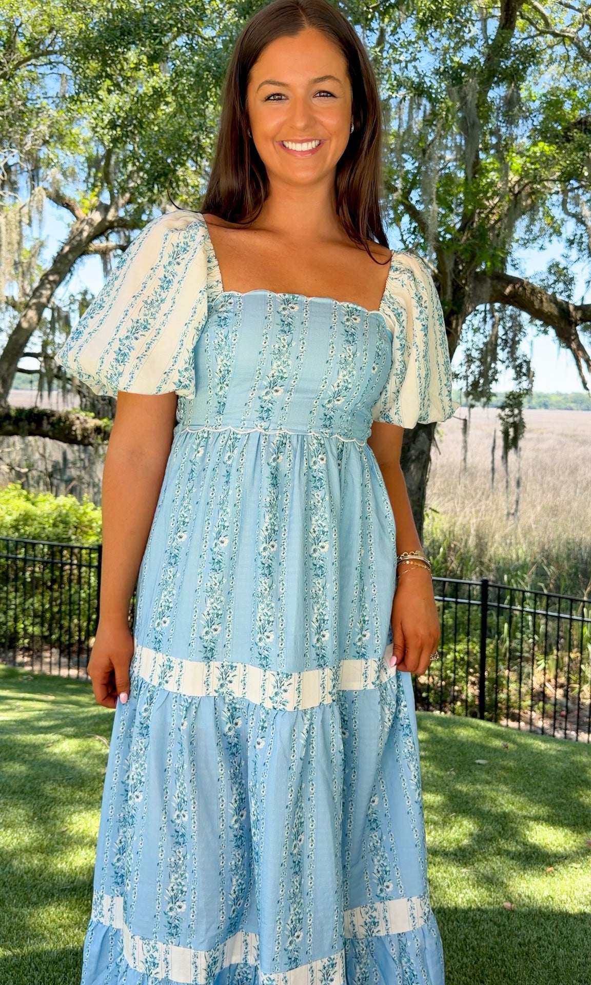 Woman wearing a light blue dress with white patterns outdoors.