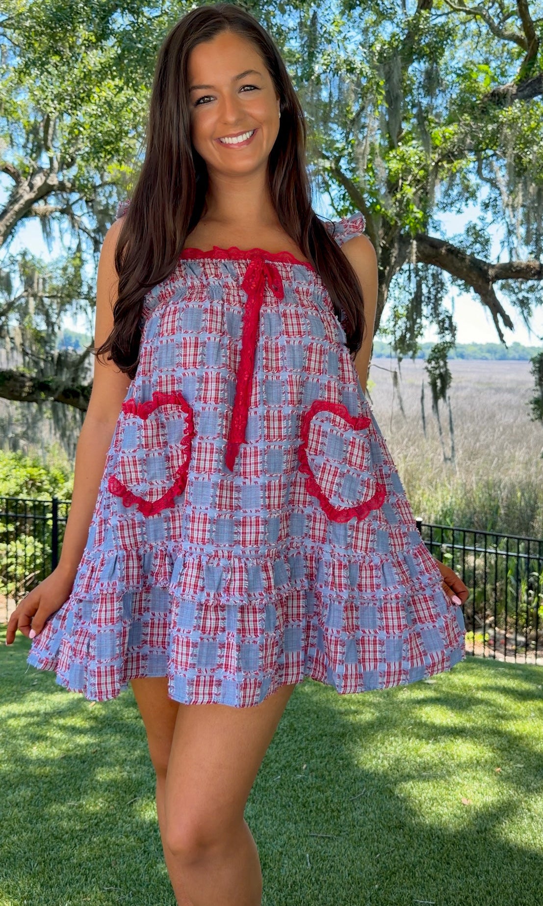 Woman wearing a blue and red checkered dress with heart designs outdoors.