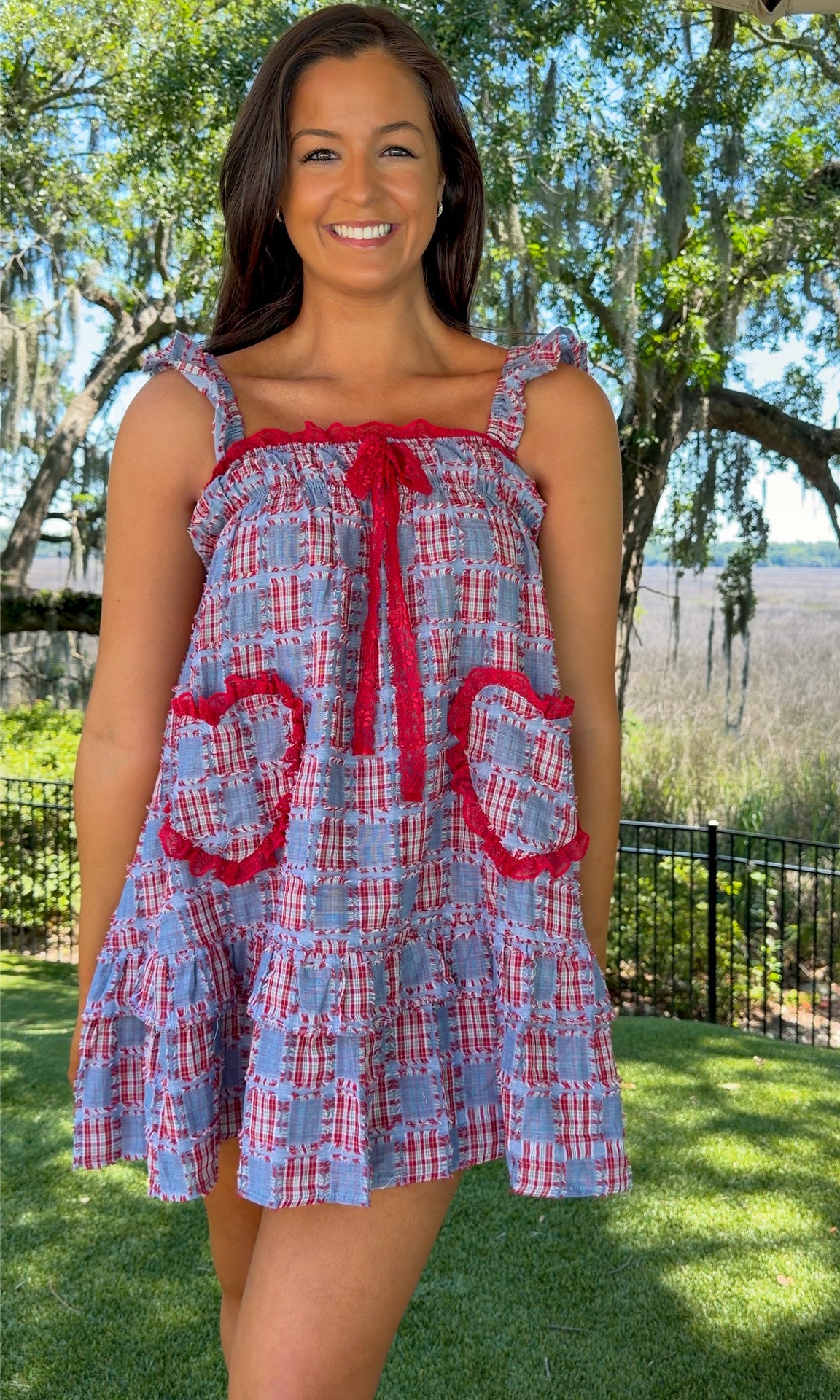 Woman wearing a blue and red checkered dress with floral details outdoors.