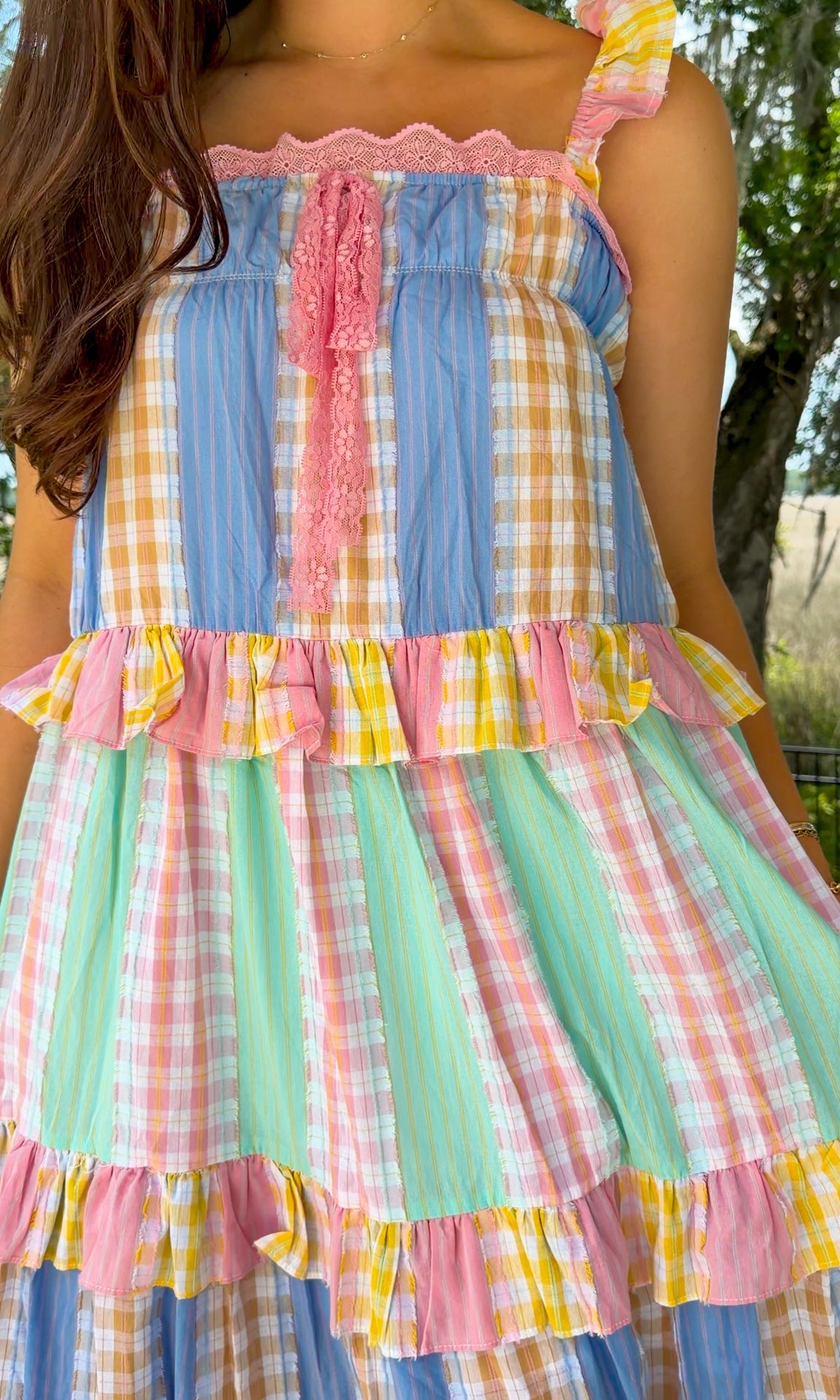 Pastel patchwork maxi dress featuring mixed check and stripe prints in pink, blue, yellow, and mint with ruffle straps, heart-shaped front pockets, lace trim, and a relaxed flowy silhouette.