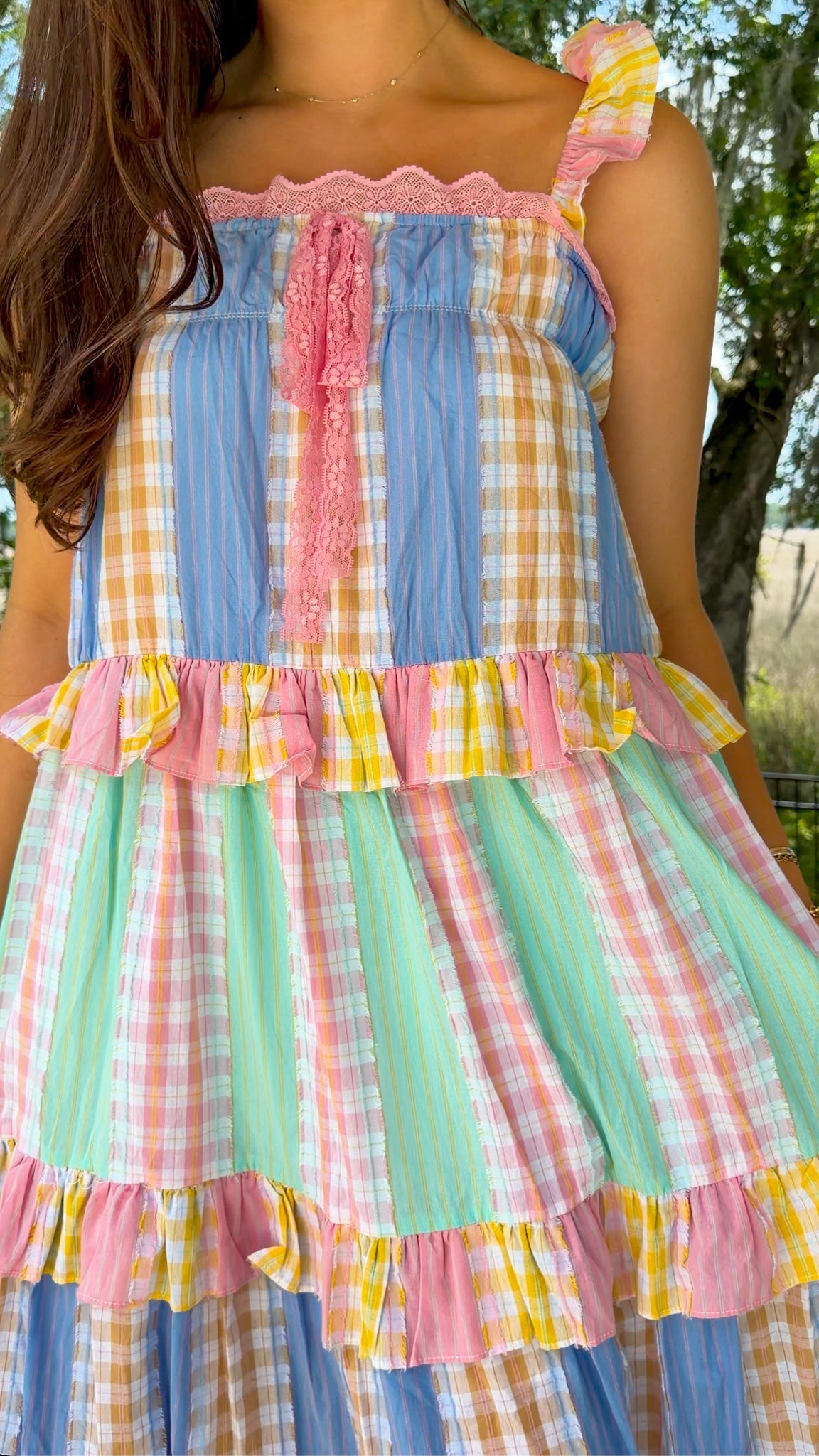 Pastel patchwork maxi dress featuring mixed check and stripe prints in pink, blue, yellow, and mint with ruffle straps, heart-shaped front pockets, lace trim, and a relaxed flowy silhouette.
