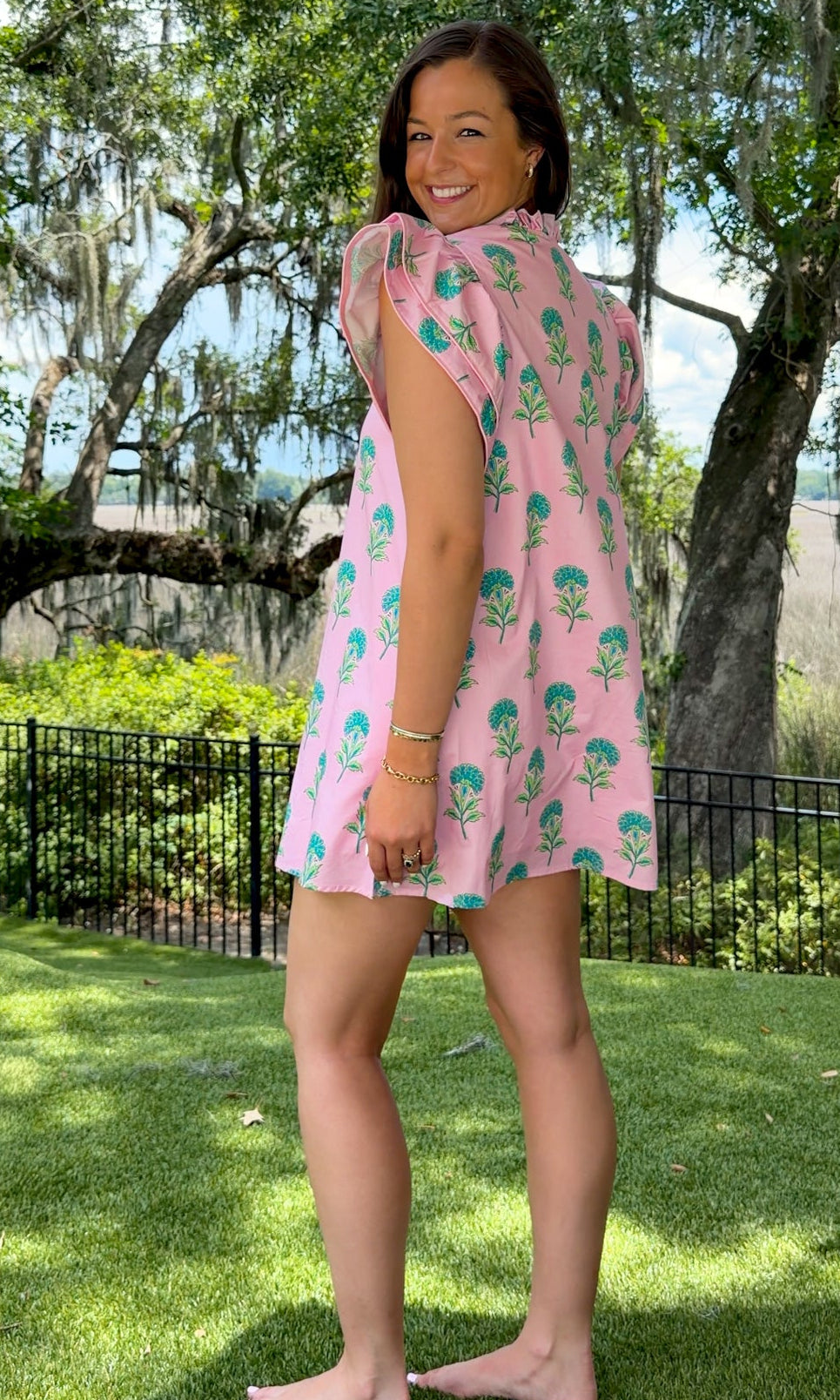 Pink and green floral mini dress with flutter sleeves, a ruffled stand neckline, decorative frog button closures, and a relaxed shift silhouette.