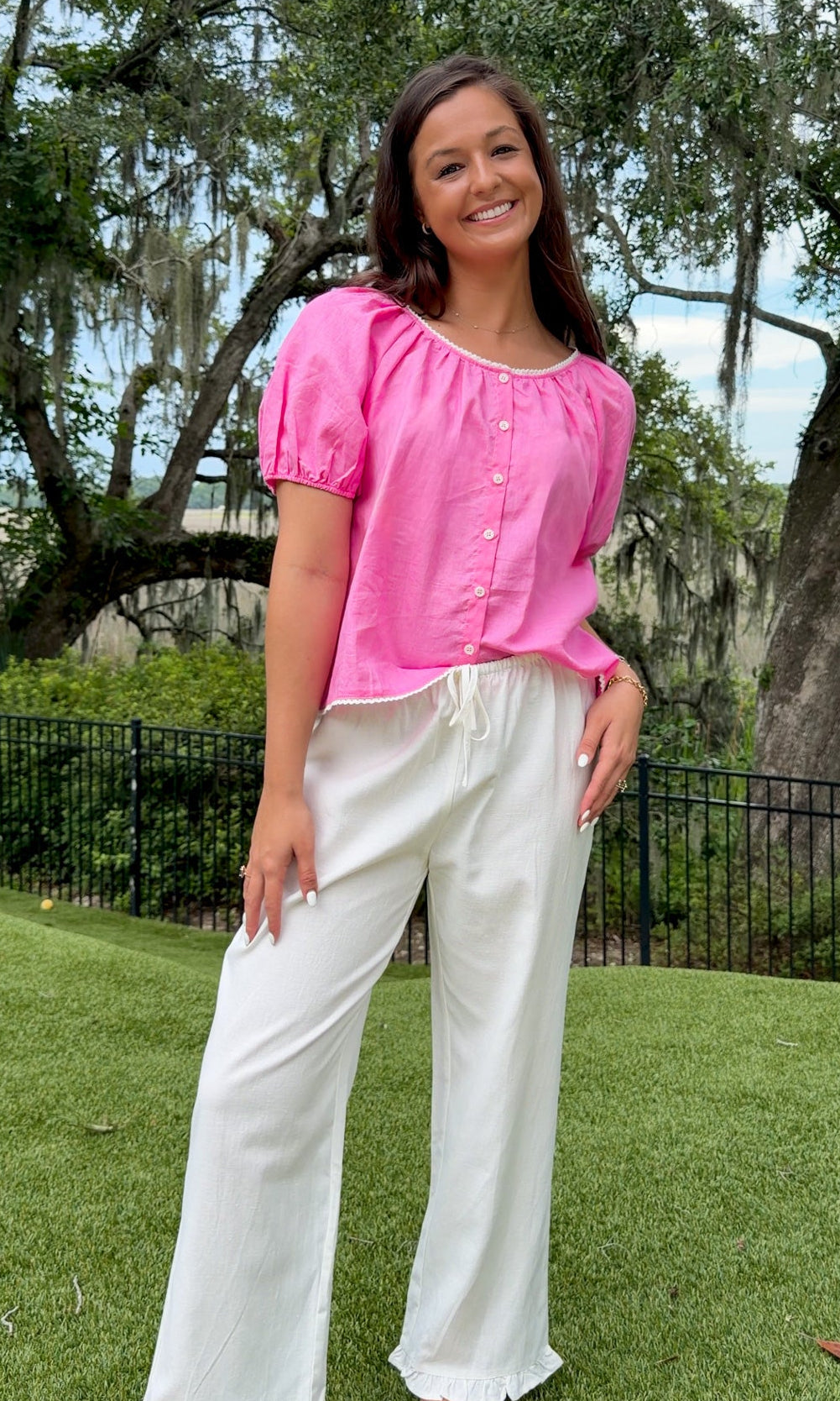White full-length straight-leg pants featuring an elastic drawstring waistband, side and back patch pockets, delicate ruffle trim at the hem, and a relaxed, lightweight fit.