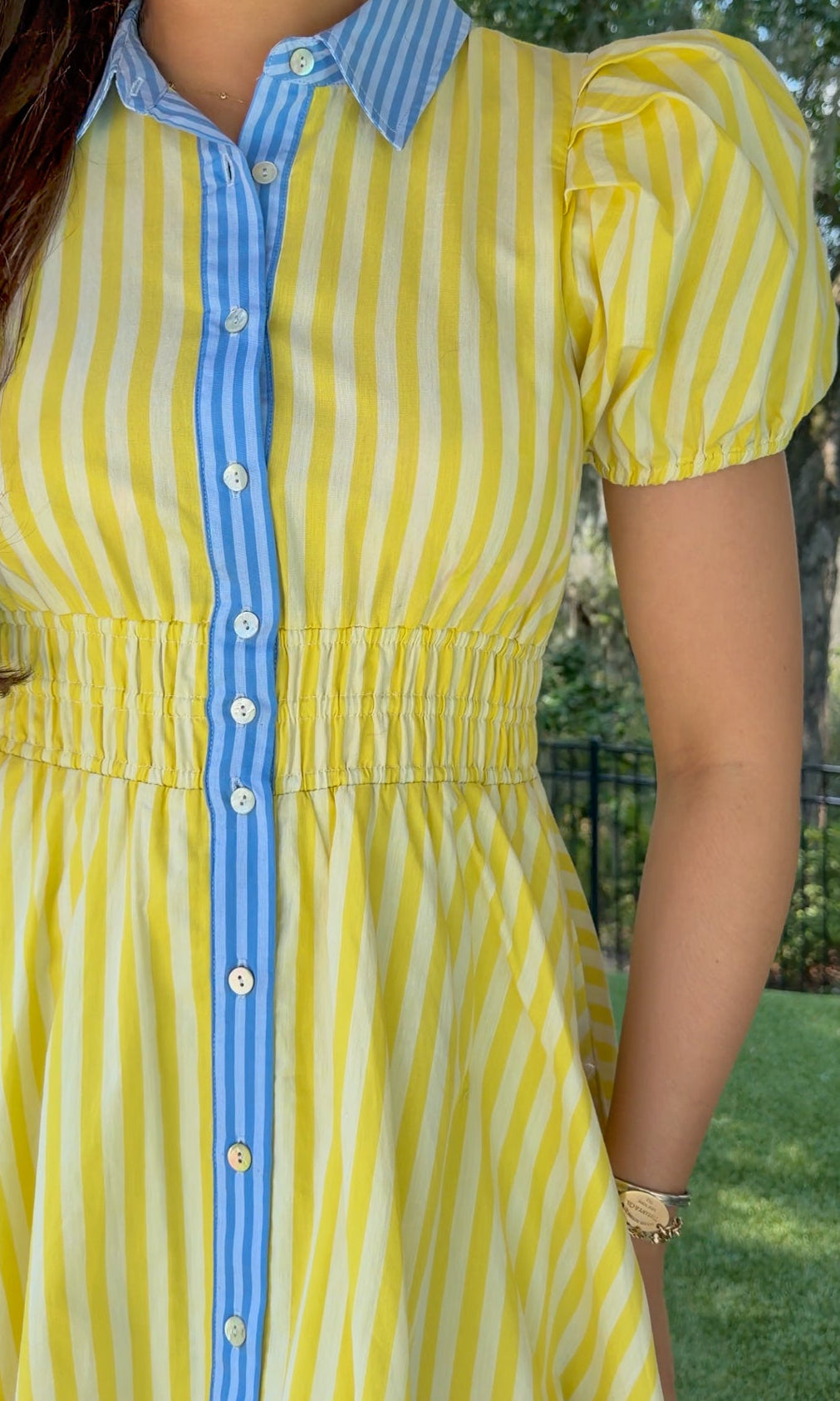 Yellow and ivory striped mini dress featuring a contrast blue collar and button placket, short puff sleeves, a smocked waist, side pockets, and a lightweight lined silhouette.