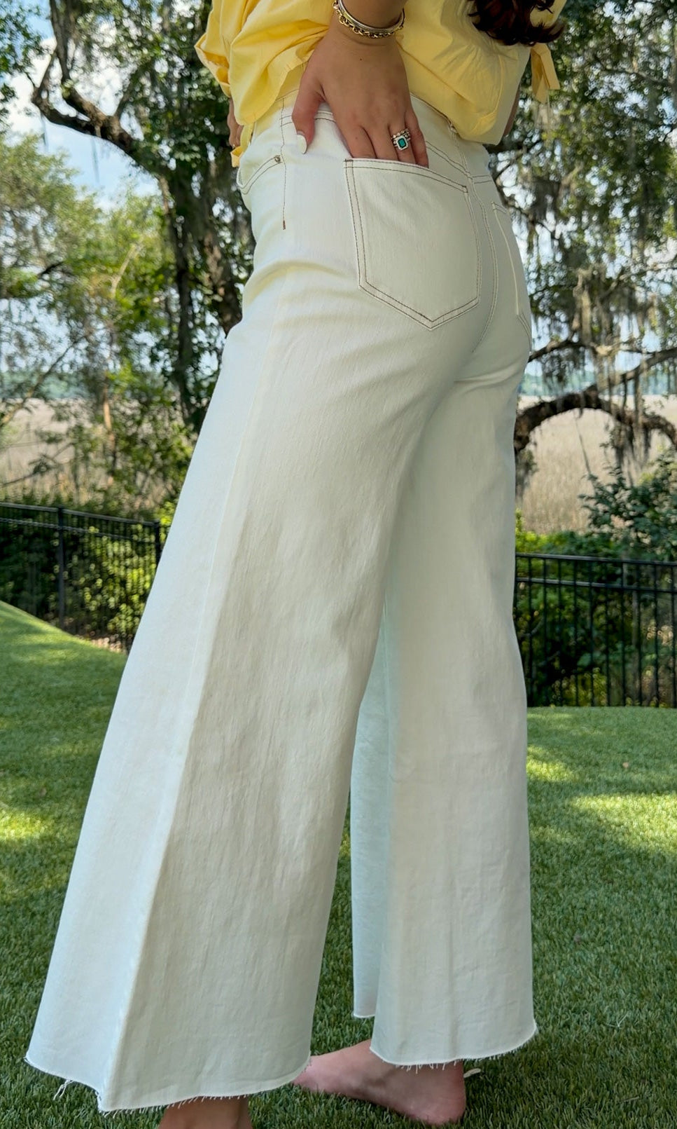 White high-rise wide leg denim jeans featuring contrast stitching, a cropped raw hem, front and back pockets, and a flattering structured fit.