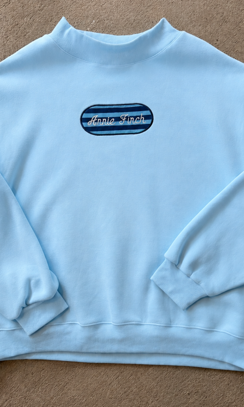 light blue mockneck sweatshirt with patch striped with embroidered annie finch