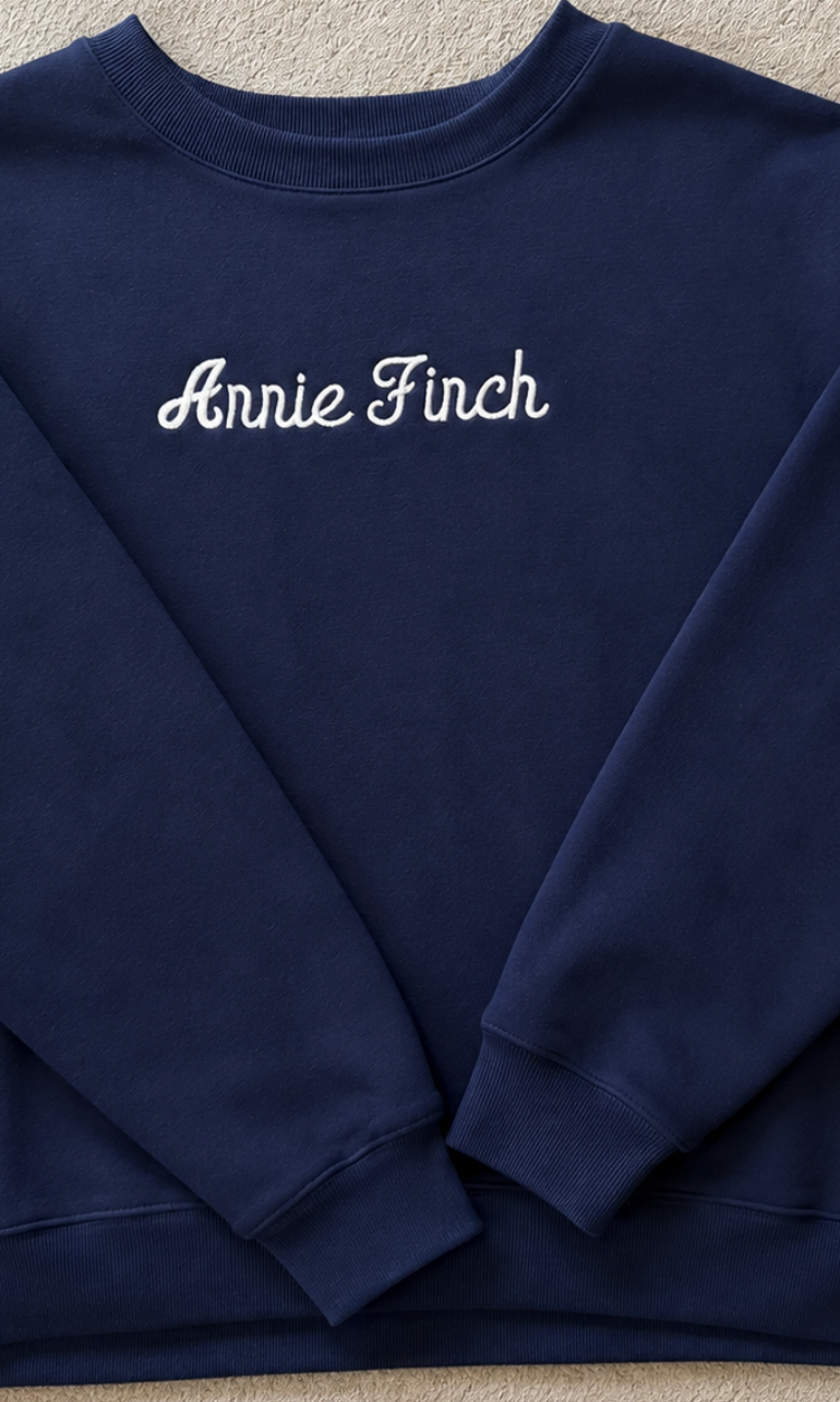 navy crewneck with white "annie finch" script embroidered on front