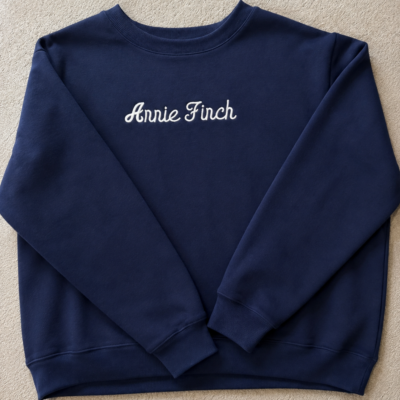 navy crewneck with white "annie finch" script embroidered on front