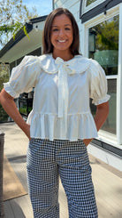 white cotton blouse with peter pan collar, puff sleeves, tie front bow and peplum hem