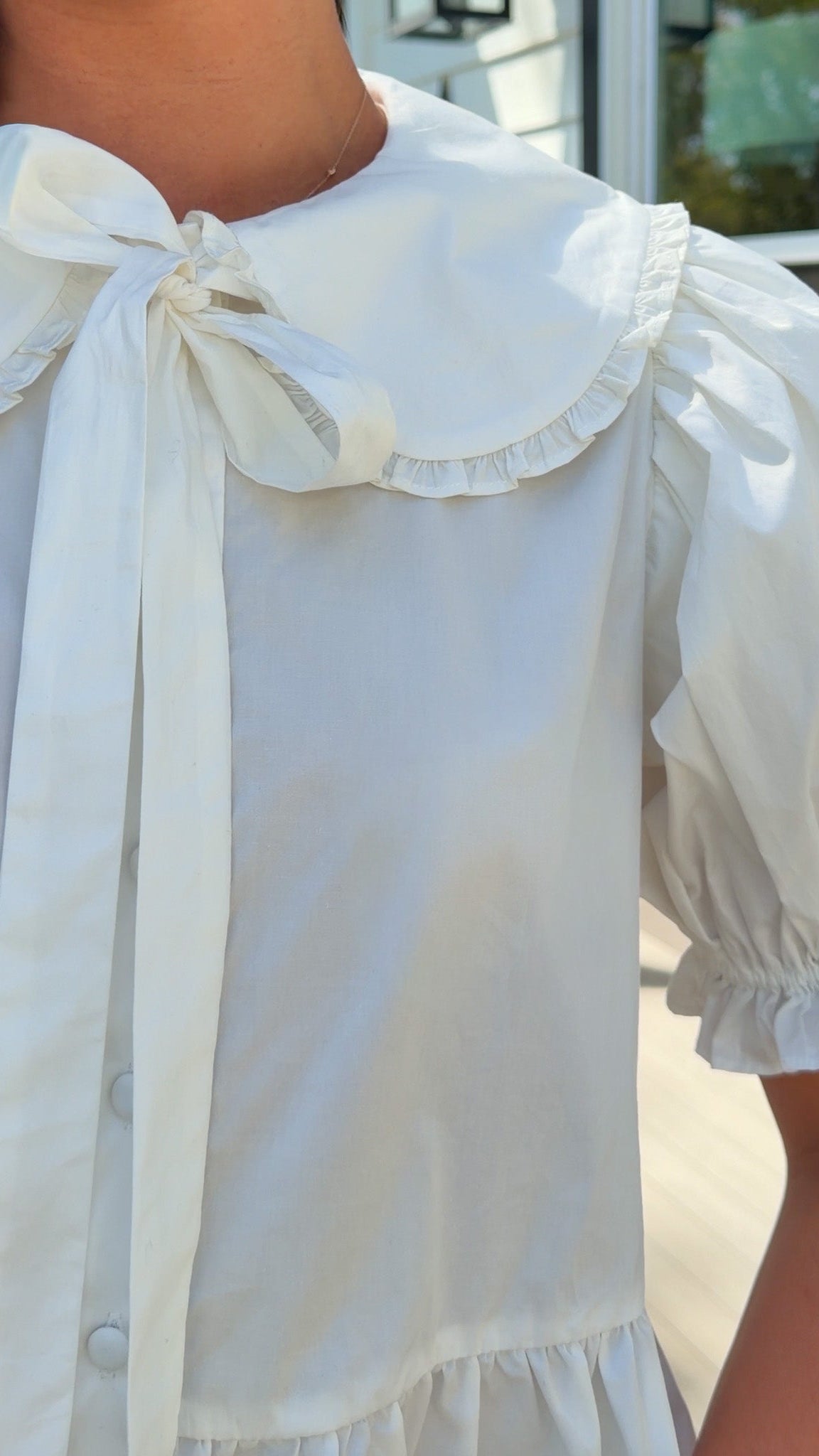 white cotton blouse with peter pan collar, puff sleeves, tie front bow and peplum hem