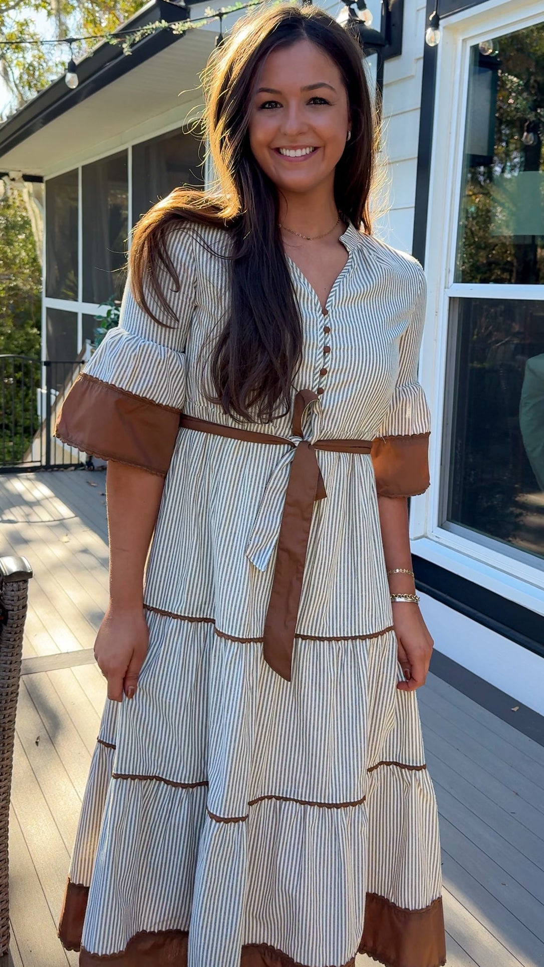 beige midi dress with brown stripes and details and belt front close