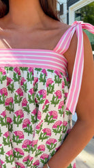 Woman wearing a floral dress with pink straps in an outdoor setting