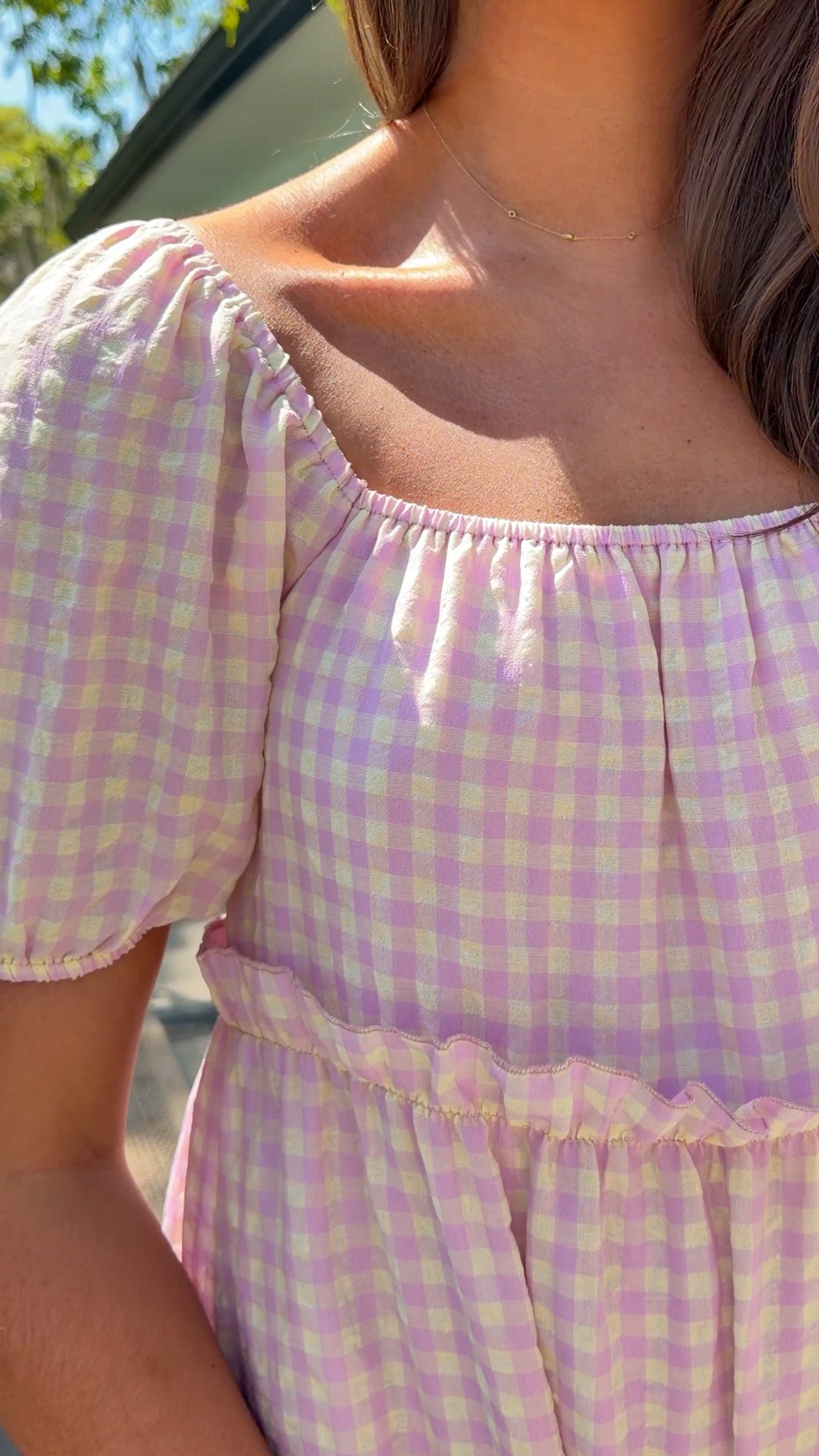Person wearing a pink and yellow checkered dress with a blurred background