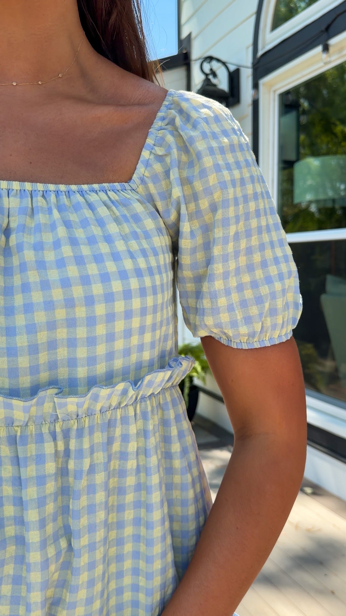Person wearing a blue and yellow checkered dress with a blurred background