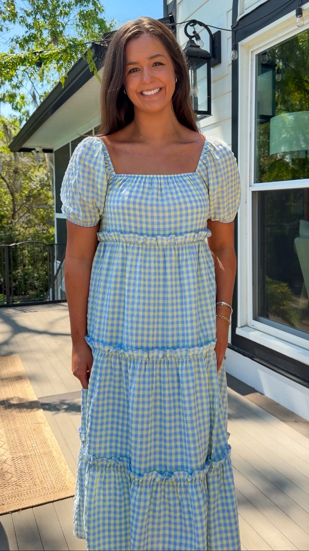 Woman wearing a blue and white checkered dress standing outdoors.