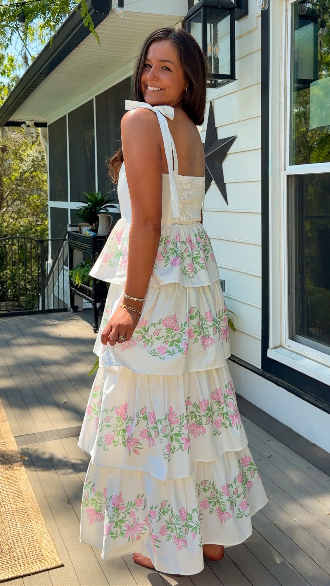 Woman in a floral dress standing on a porch with a star decoration.