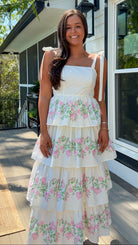 Woman wearing a floral dress standing on a porch.