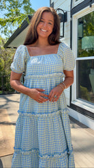 Woman wearing a blue and white checkered dress standing outdoors.