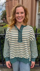 Woman wearing a striped shirt with green accents standing outdoors.