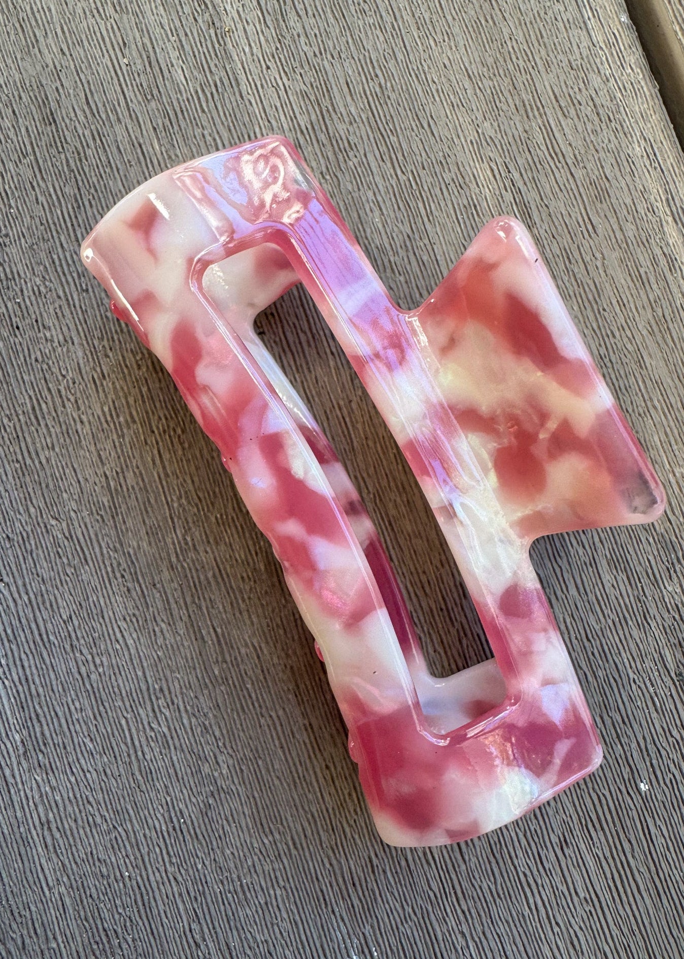 Pink and white marbled hair clip on a wooden surface