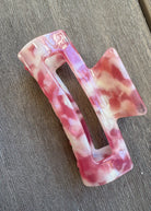 Pink and white marbled hair clip on a wooden surface