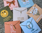 Collection of necklaces on cards with various designs and text.