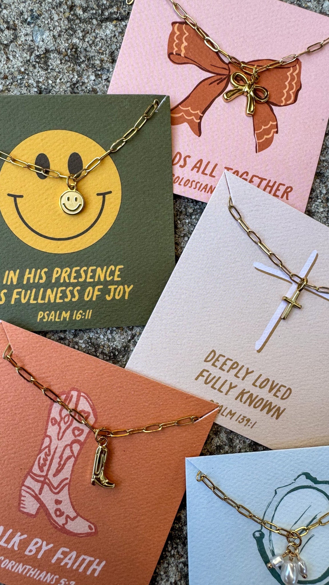Collection of gold necklaces on various cards with motivational messages.