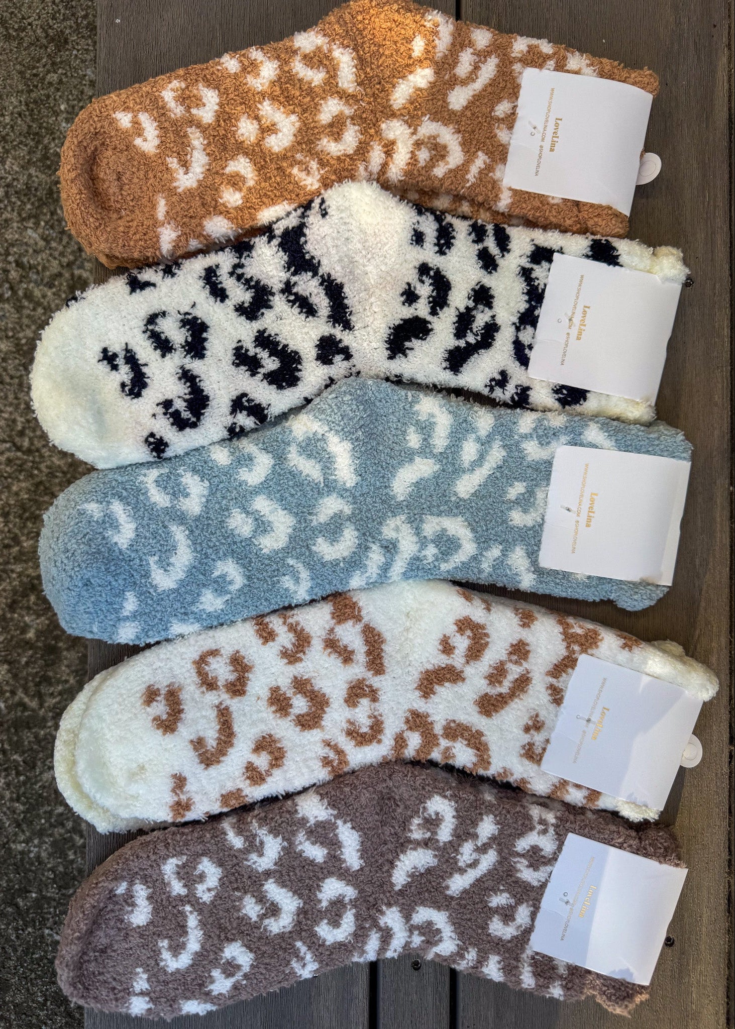 Five pairs of leopard print socks in different colors on a wooden surface.