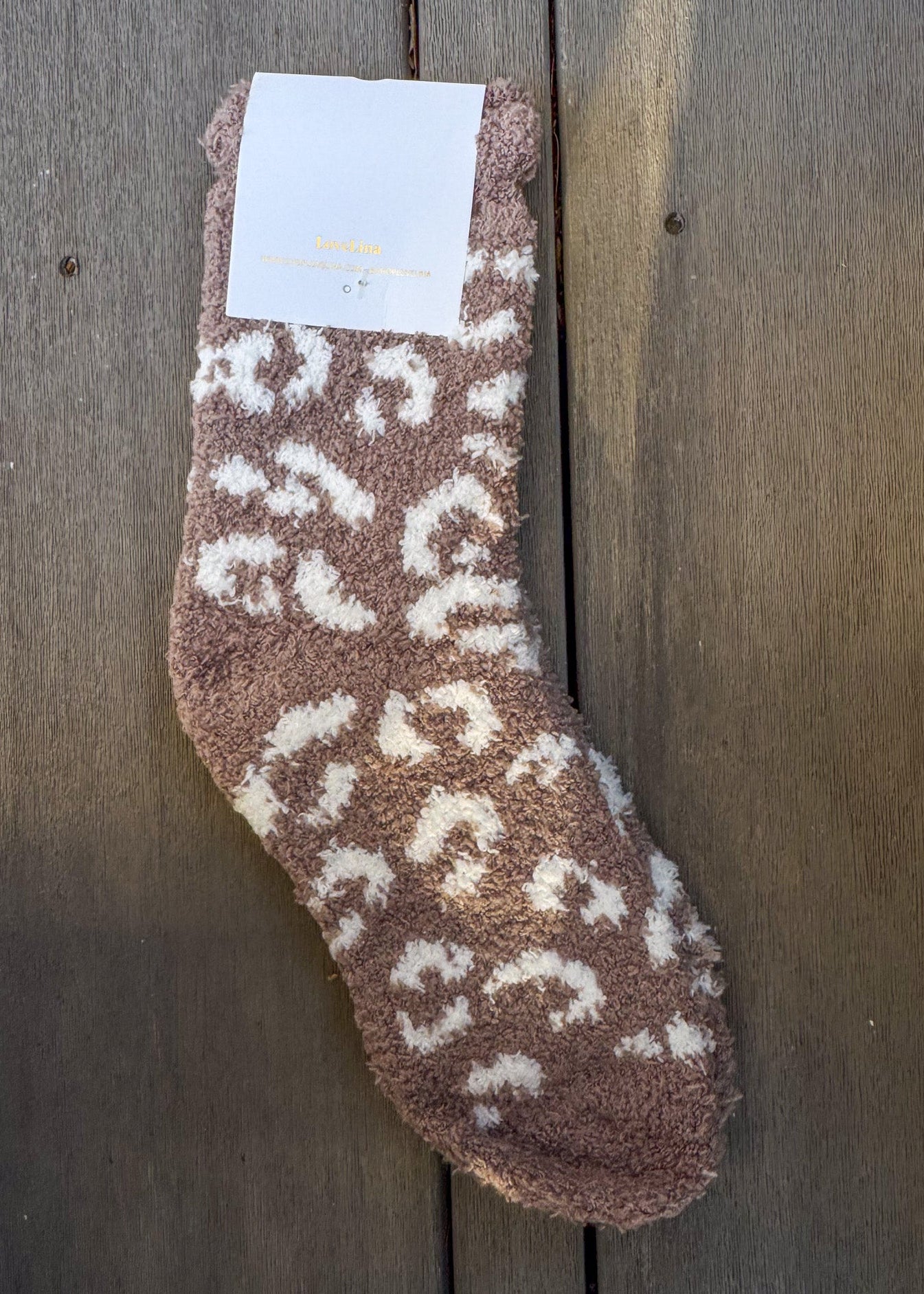Brown fuzzy sock with white patterns on a wooden surface