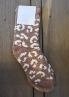 Brown fuzzy sock with white patterns on a wooden surface