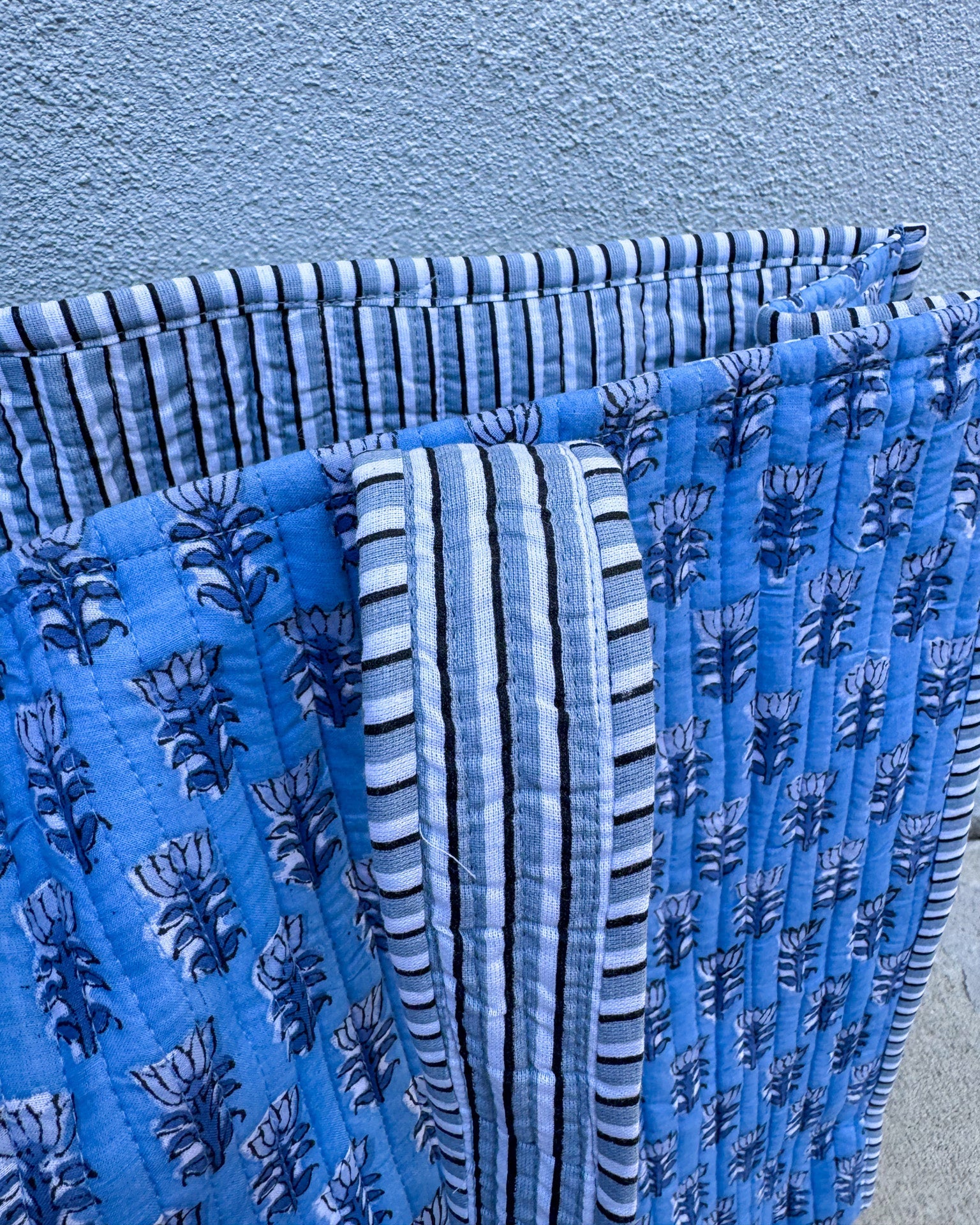 Stack of blue patterned fabrics against a light blue background