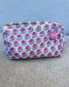 Fabric pouch with pink floral pattern on a concrete surface and blue wall background