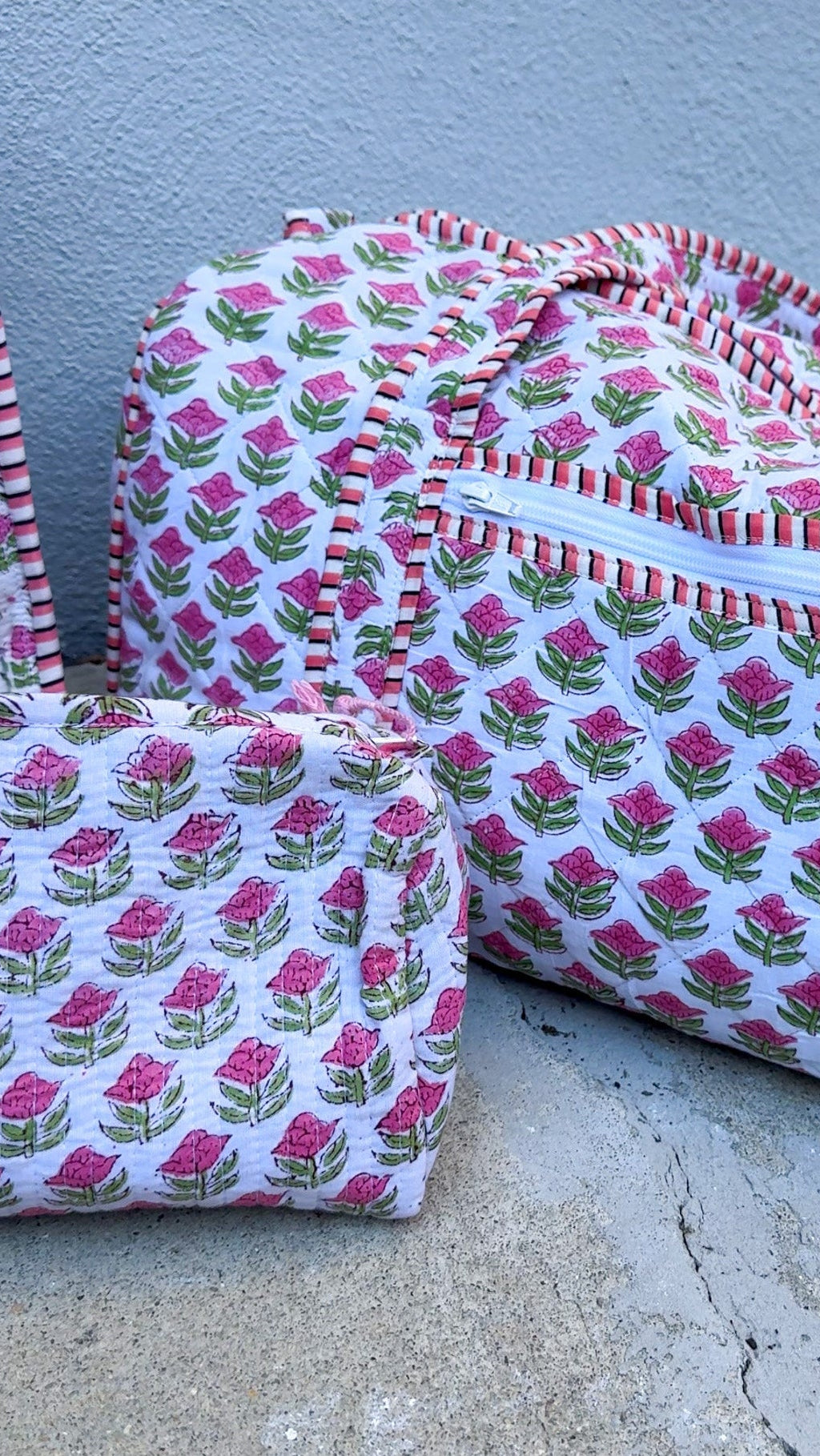Two fabric bags with pink floral pattern on a concrete surface.