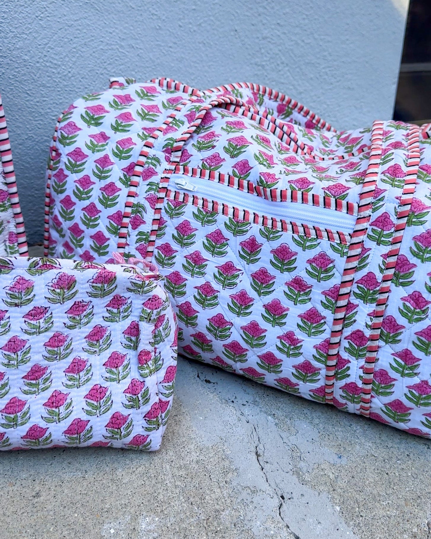 Two fabric bags with pink floral pattern on a concrete surface.