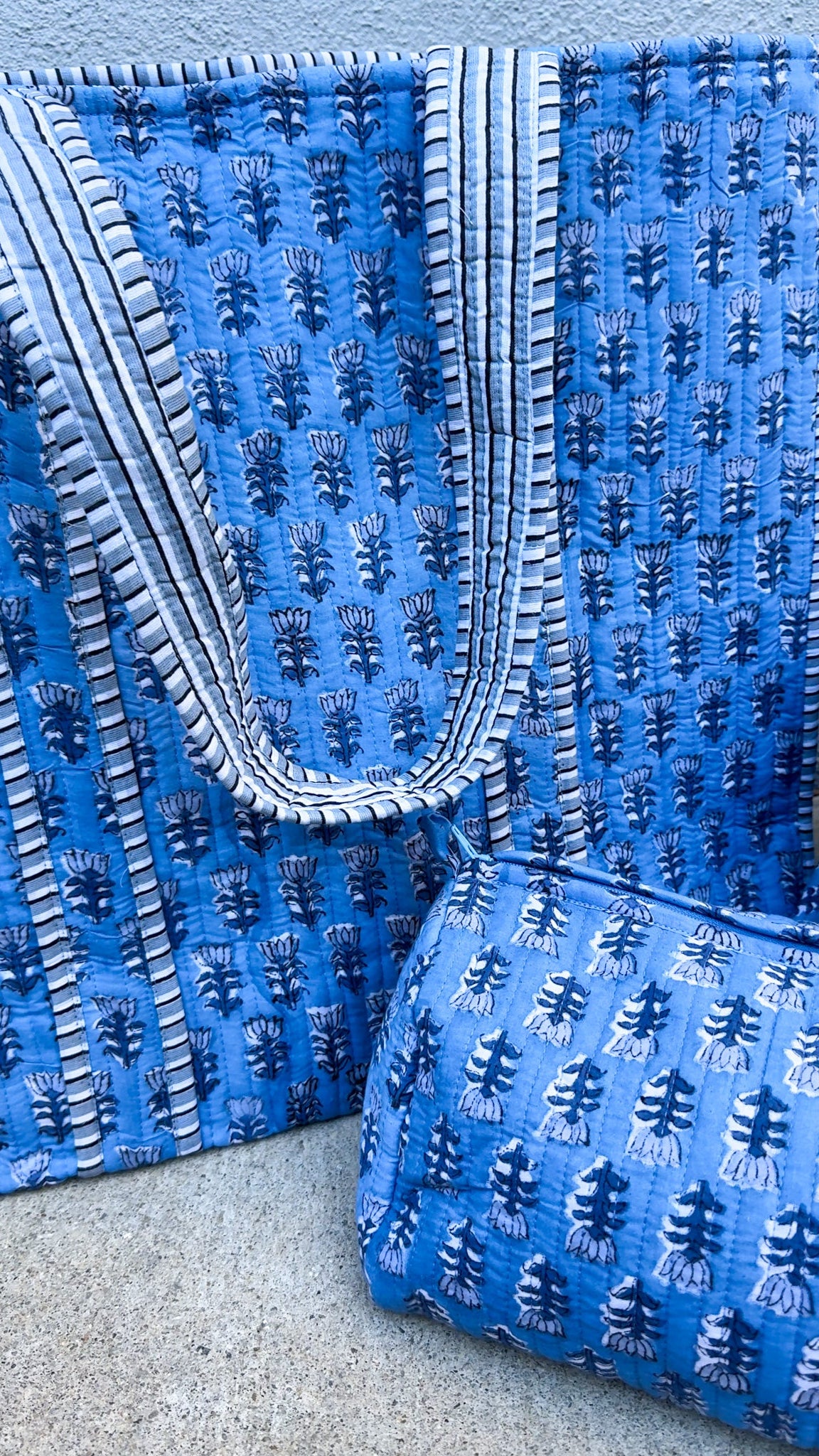 Blue embroidered bag with a textured pattern on a gray surface