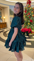 Hunter green floral textured mini dress with puff sleeves, covered button details, tie waist, and tiered skirt.