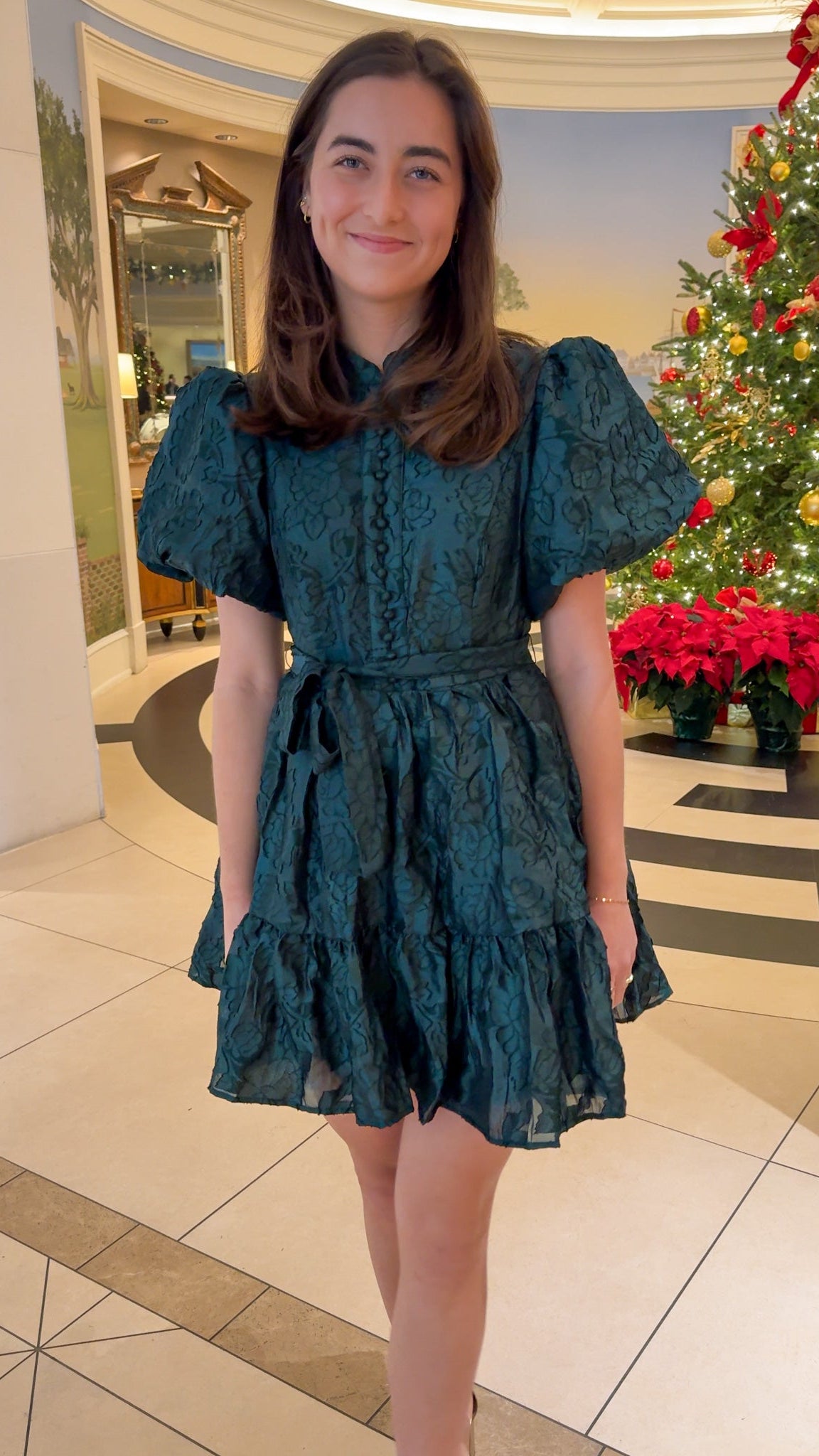 Hunter green floral textured mini dress with puff sleeves, covered button details, tie waist, and tiered skirt.