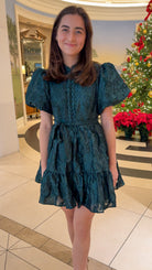 Hunter green floral textured mini dress with puff sleeves, covered button details, tie waist, and tiered skirt.