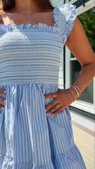 Woman wearing a blue and white striped dress with ruffled sleeves.