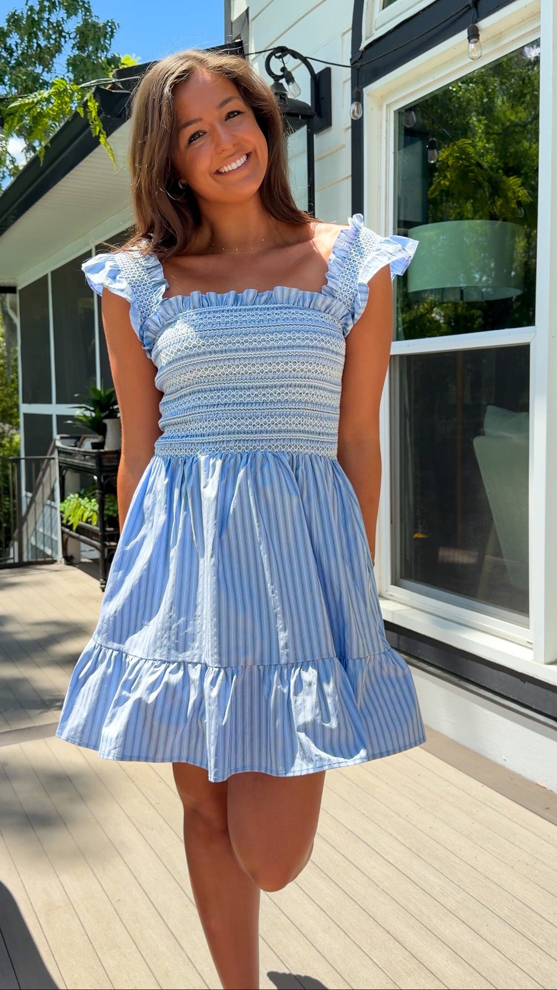 Woman wearing a blue and white striped dress standing outdoors.