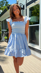 Woman wearing a blue and white striped dress standing outdoors.