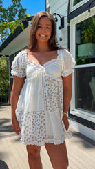 cream floral mini dress with eyelet lace, puff sleeves, scalloped neckline, and front tie detail
