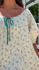 cream floral romper with puff sleeves and green tie neckline, flowy fit with built-in shorts