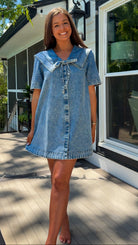 light wash denim mini dress with oversized collar, tie front detail, short sleeves, and slightly oversized fit