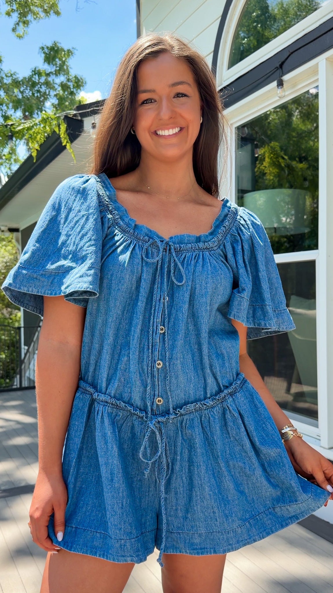 Denim romper with butterfly sleeves, tie neckline, and drawstring waist in blue