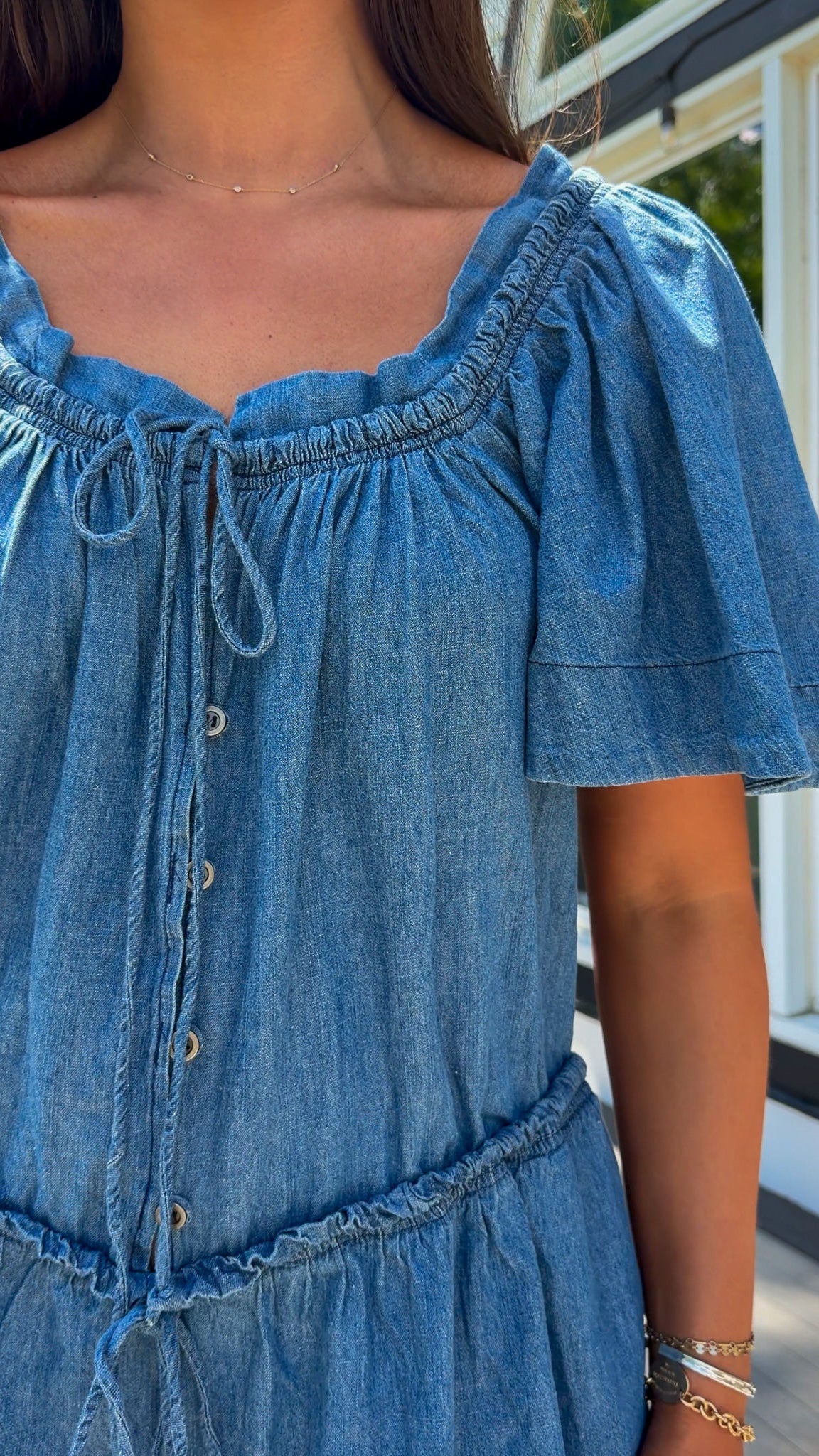 Denim romper with butterfly sleeves, tie neckline, and drawstring waist in blue