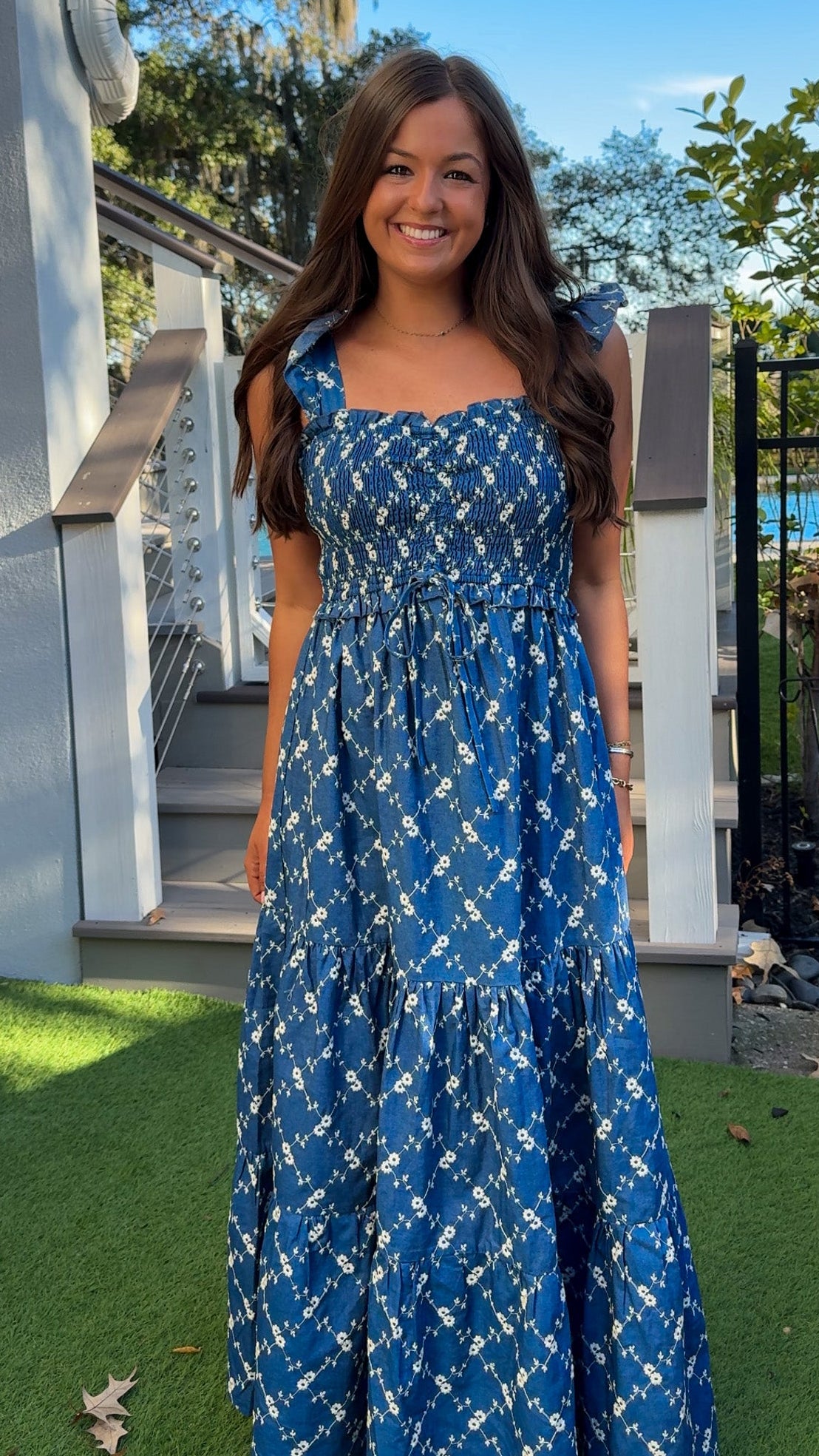 Denim blue and off-white floral tiered maxi dress with smocked bodice and flutter straps.