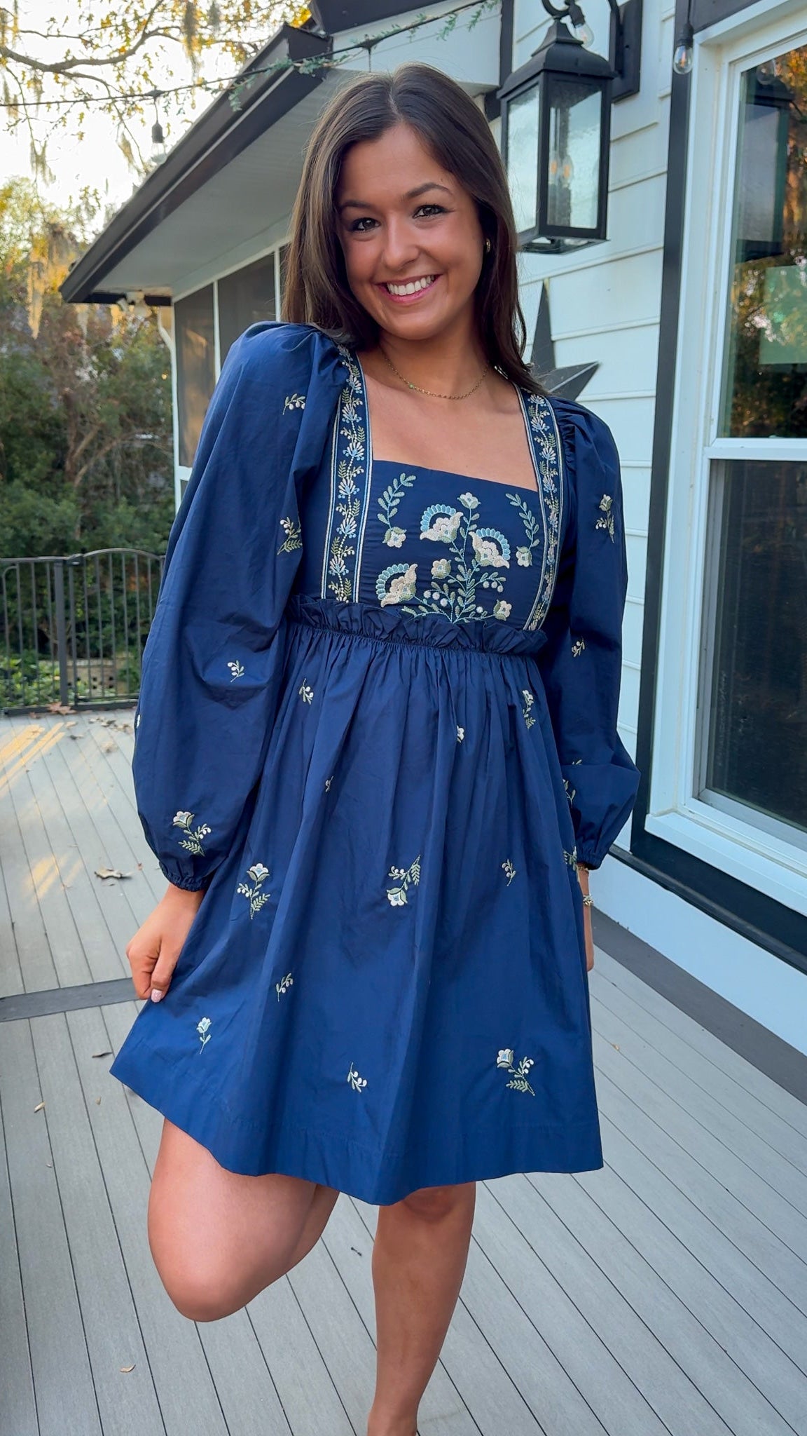 Navy long sleeve babydoll mini dress with floral embroidery detail and relaxed silhouette.